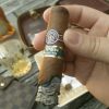 Half smoked montecristo eagle open series cigar with glass of alcohol and bottle in the background