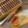 Image of cuban Cigar over the glass of alcohol with habanos hecho en cuba box in the background
