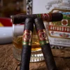 3 cigars close up shot with cigar humidor box in background and alcohol